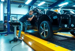 mechanic checking car's wheel alignment and steering alignment using advanced tools in a high-tech automotive workshop